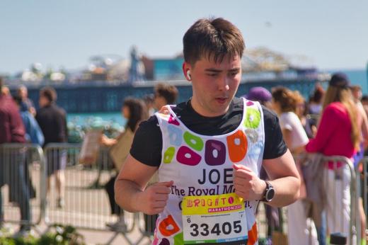 Royal Marsden runner looking down with headphones on. There is the pier in background