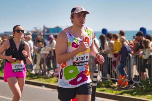 Royal Marsden runner with hat on, running past the supporters along the seafront.