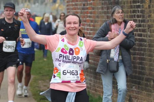 RMCC runner smiling as she's running with her arms in the air and runners in the background