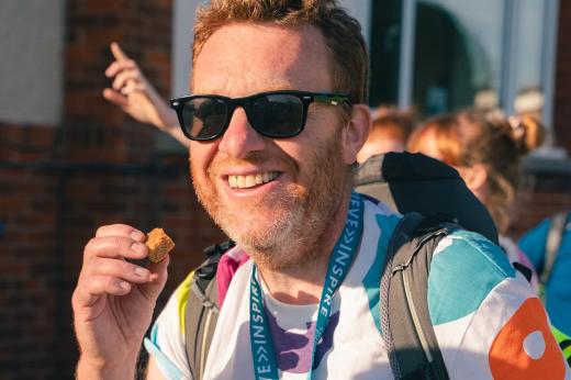 RMCC trekkers smiling and eating a snack at the end of the hike with sunglasses and a medal on