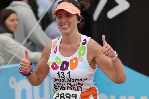 RMCC runner smiling with her thumbs up while running past the supporters