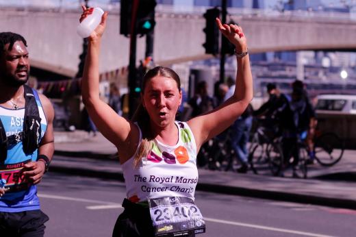 RMCC runner cheering with her hands in the air as she runs past supporters 