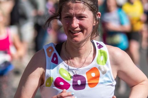 RMCC runner smiling while running in the sun past the cheering crowds