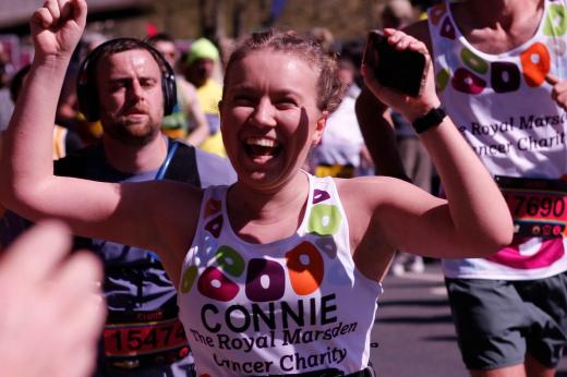 RMCC runner smiling and cheering with her hands in the air whilst running past cheering crowds