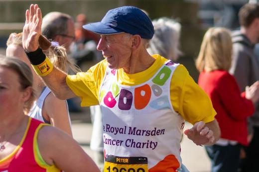 RMCC runner smiling and waving to people with a hat on