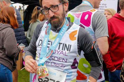 RMCC runner and staff member smiling with his medal after finishing the run