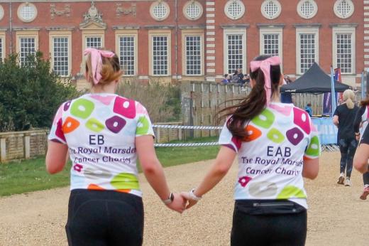 RMCC runners photographed from behind as they run hand in hand towards the finish line