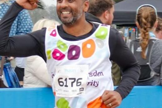 Royal Marsden runner smiling as he runs past the cheering crowd with his fist in the air