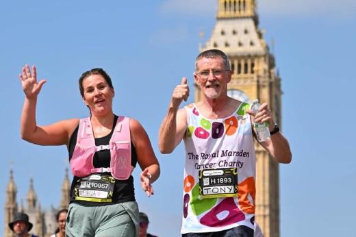 RMCC runner with daughter running and smiling at the camera whilst running through London with Big Ben in the background. 