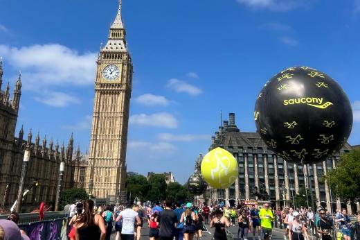 Big Ben and Saucony balloon on a blue sky day with runners in the foreground. 