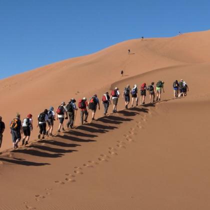 Trekkers climbing dune
