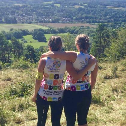 Two female runners take in view, hugging