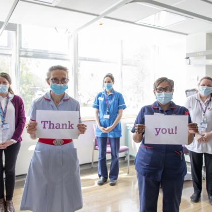 Staff standing in a group with signs saying Thank you 
