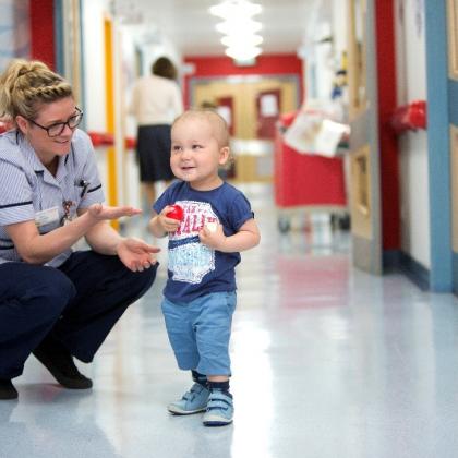 White toddler in hospital corridor with female nurse