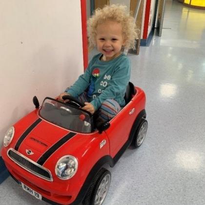 Child sitting in toy car in a hospital