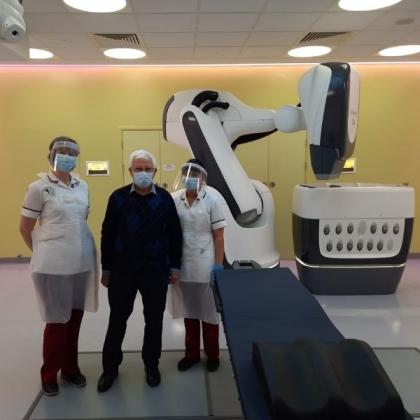 Patient standing in imaging suite with two nurses in personal protective equipment