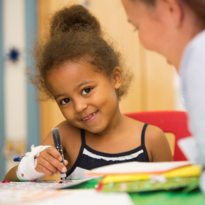 Child colouring whilst in hospital next to a nurse