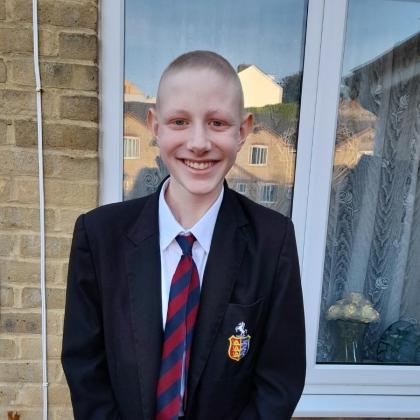 Ryan standing outside wearing his school uniform and a big smile