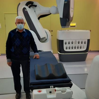 Colin stands beside the cyberknife radiotherapy equipment