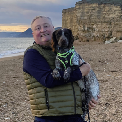 Malcolm on a beach holding his dog patch.