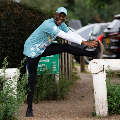 Photo of a Man in a Marsden March t-shirt and cap stretching leg on a fence post