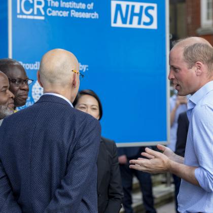 A group of men are outside having a discussion. 2 black men and 2 white men. One of the white men is The Duke of Cambridge