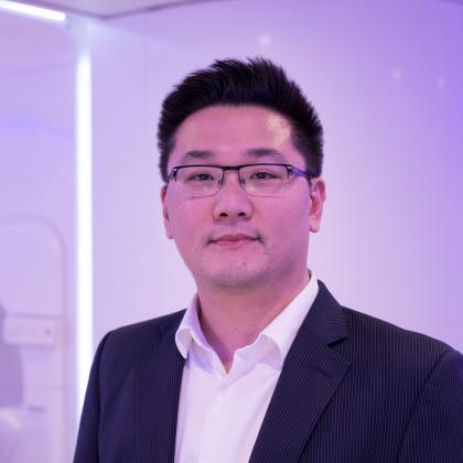 Dr Kee Howe Wong, wearing a white shirt and blue suit jacket. He has short dark hair and wire frame glasses.