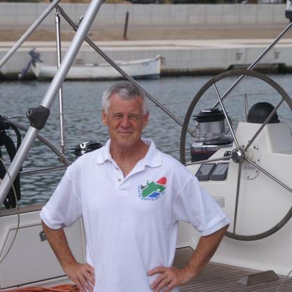 Michael Thick standing on a boat. his hands are on his hips and he is wearing a white polo shirt.