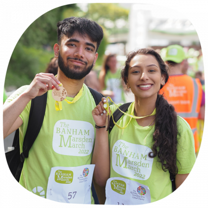 A couple at the finish line holding up their Banham Marsden March medals and smiling