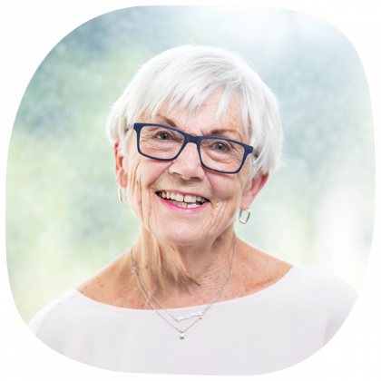 Jacky smiling. She has short white hair and wears blue rimmed glasses.