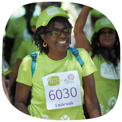 A woman taking part in the Banham Marsden March. She is smiling and wearing the Banham Marsden March t-shirt and cap.