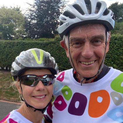 Chris and Carolyn wearing their Royal Marsden cycling shirts, bike helmets and sunglasses. 