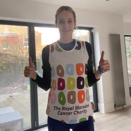 A woman in a Royal Marsden running vest smiling and giving a thumbs