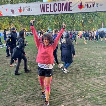 A woman in running gear smiling with her hands up