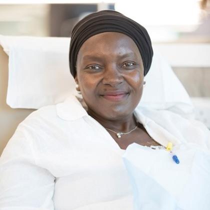 The head and shoulders of a woman sitting on a hospital chair, receiving chemotherapy