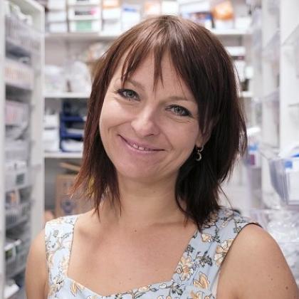 Headshot of a person standing in a room with pharmacy medications filed away in drawers on the wall.