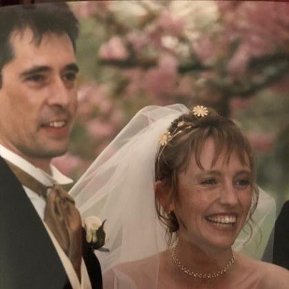 A bride with a white flowery veil and a groom in smart suit smiling on their wedding day