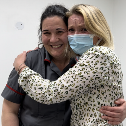 A Royal Marsden nurse in uniform smiling and hugging a patient