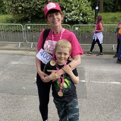 A mother in bright pink Banham Marsden March merch, with her arm around her young son wearing a medal