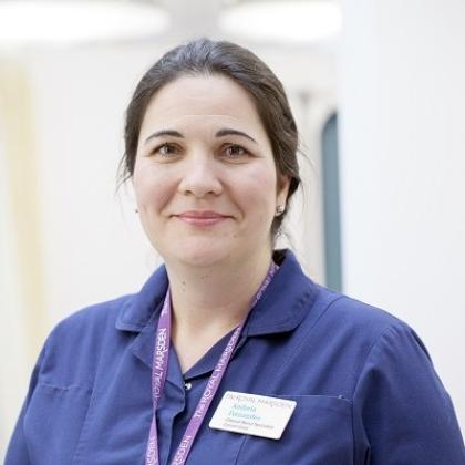 Headshot of a nurse wearing a blue shirt and purple lanyard