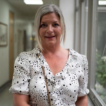 A Royal Marsden patient standing in a hospital hallway, wearing a white spotty dress and smiling