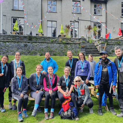 A group of Lake District Triple Challenge finishers in front of the hotel with their medals