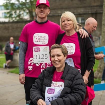 A Royal Marsden patient in a wheelchair with two people behind, they're all wearing Banham Marsden March t-shirts. 