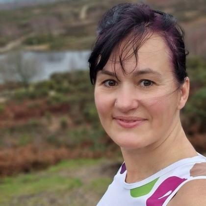 Headshot of a person in the hilly countryside, smiling and wearing a Royal Marsden Cancer Charity branded vest.