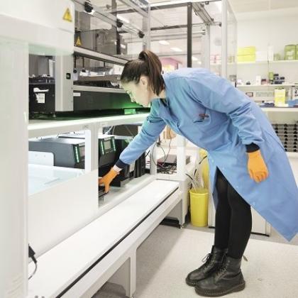 The Royal Marsden's Innovation Lead in a lab coat looking at the Automata robot