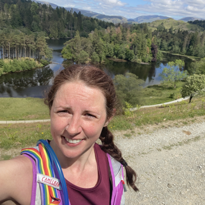 Selfie of Jo with trees and a lake behind her