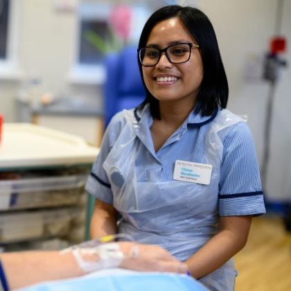 A member of staff at The Royal Marsden smiling at a patient who is receiving treatment in the medical day unit