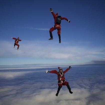 Three people free-falling wearing santa costumes