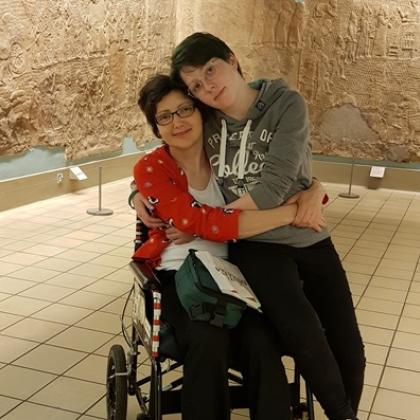 A woman in a wheelchair with her daughter, hugging and looking at the camera