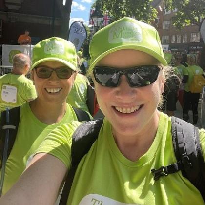 Amanda in a bright green Banham Marsden March t-shirt and hat, smiling with a friend